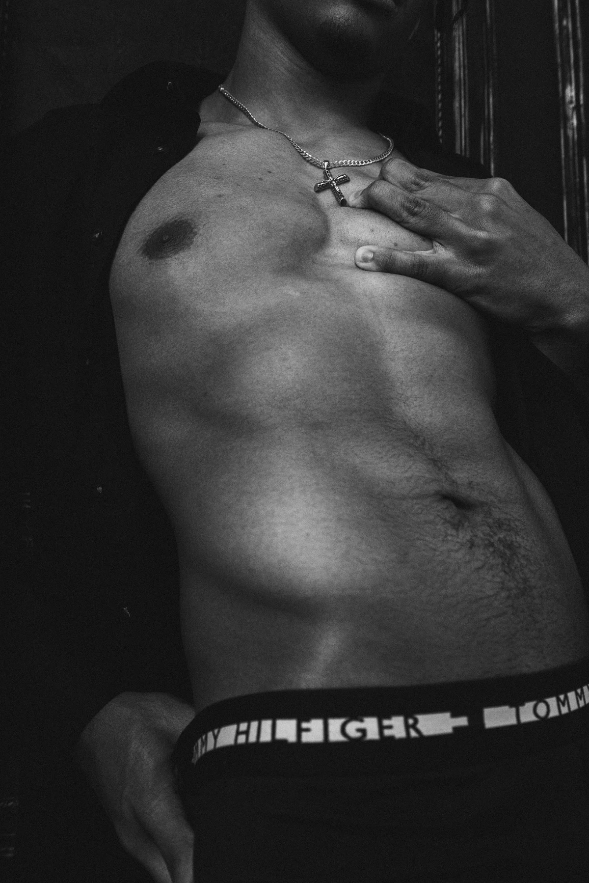 Black and white photo of a shirtless man's torso wearing a necklace and Tommy Hilfiger underwear