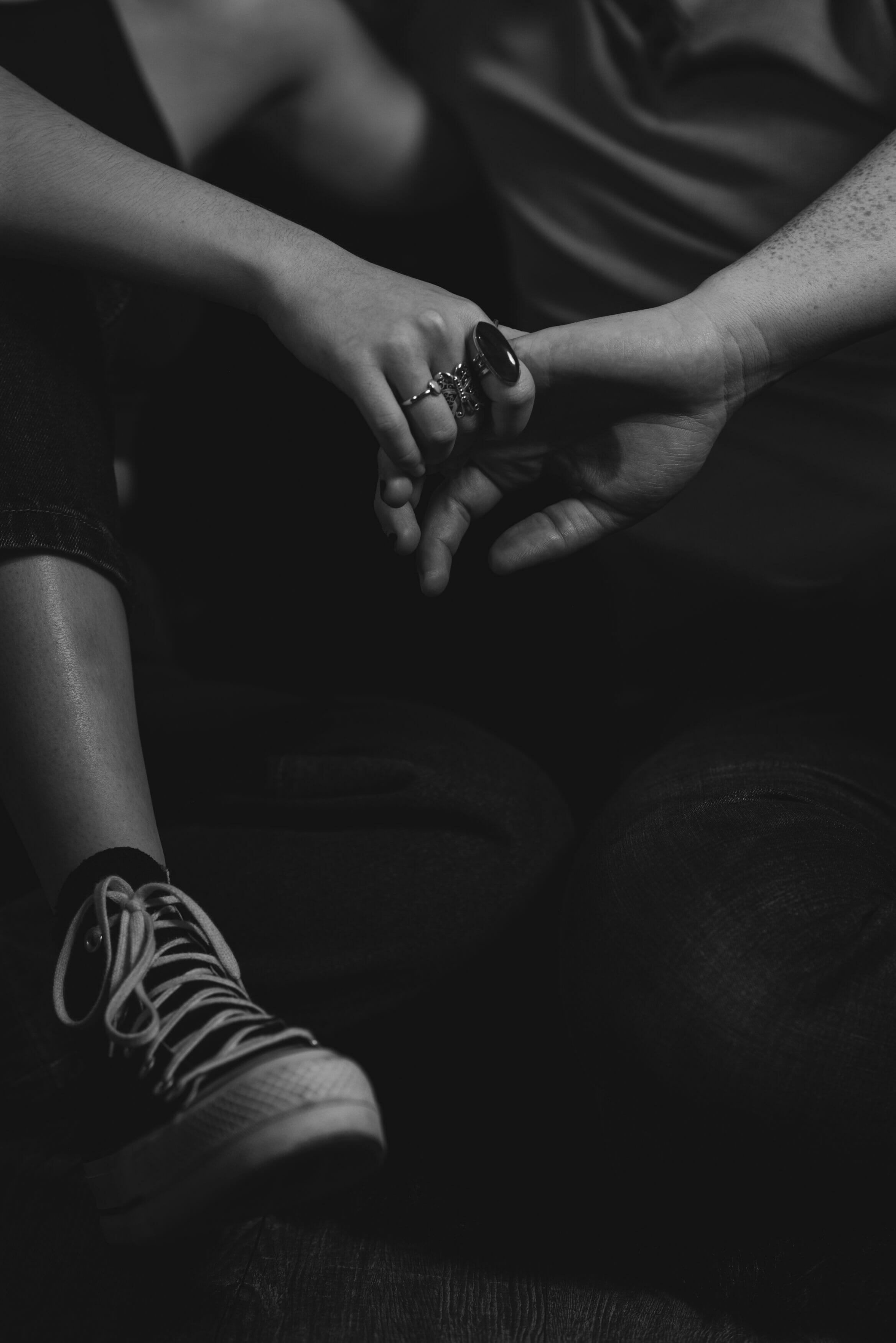 Black and white image of a couple sitting closely together, holding hands.